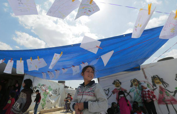 فتاة أسفل رسومات لأطفال سوريين في مخيم للاجئين (بر إلياس- البقاع اللبناني)