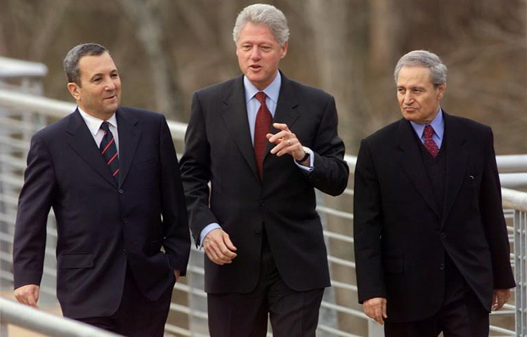 US President Bill Clinton (C) escorts Israeli Prime Minister Ehud Barak (L) and the Syrian Foreign Minister Farouq al-Shara (R) along a bridge to the US Fish and Wildlife Service Center 03 January 2000 in Shepherdstown, West Virginia. The three leaders met for the second round of Middle East peace talks in the United States. (ELECTRONIC IMAGE) AFP PHOTO/Stephen JAFFE
