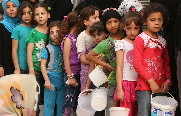 أطفال سوريون ينتظرون سللهم الغذائية في مناطق المعارضة في حلب - أيلول 2015 (AFP)