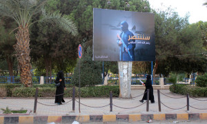 Women wearing a niqab, a type of full veil, walk under a billboard erected by the Islamic State (IS) group as part of a campaign in the IS controlled Syrian city of Raqqa on November 1, 2014. Arabic writting on billboard 