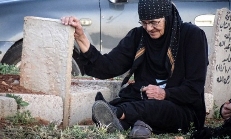 امرأة مسنة تجلس عند قبر ابنها الذي قتل في اشتباكات ضد قوات الأسد في درعا 7 نيسان 2016 (AFP)