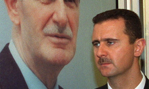 DAMASCUS, SYRIA:  (FILES) -- File picture dated 24 April 2000 shows Syrian President Bashar al-Assad standing next to a portrait of his late father Hafez al-Assad in Damascus. The Syrian president was re-elected secretary general of Syria's ruling Baath party 09 June 2005 at the end of the party's four-day congress, the official news agency SANA announced. The Baath party, which been in power since 1963, adopted 