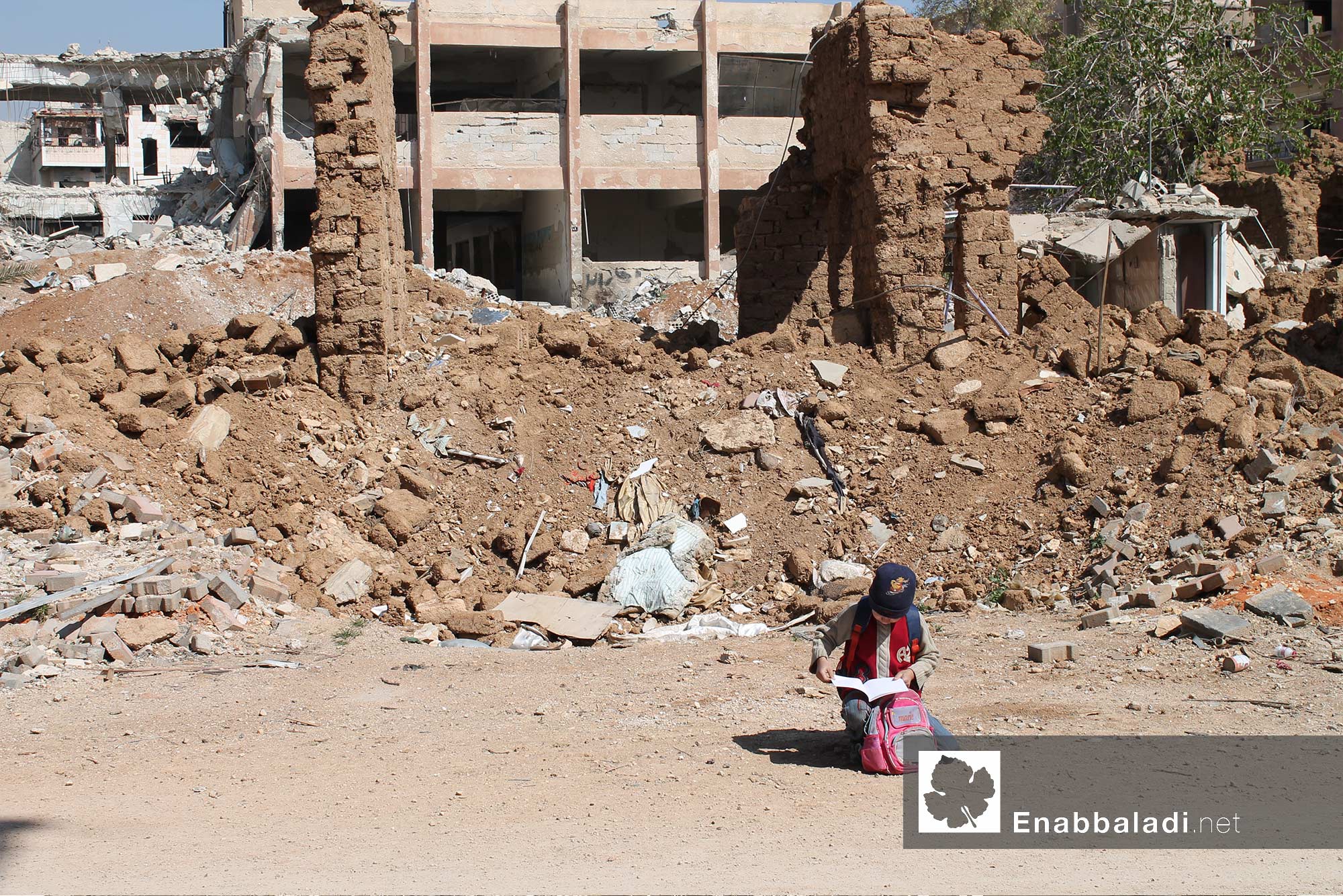 طفلة تقرأ أمام مدرسة مهدمة جراء القصف على داريا بريف دمشق- 30 آذار 2016 - (عنب بلدي)