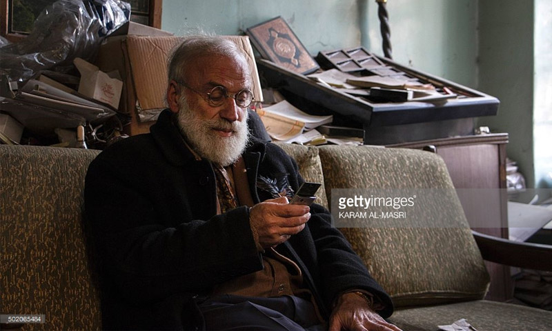 أبو عمر جامع تحف كلاسيكية (69 عامًا) يحمل هاتفه في حلب (كرم المصري - جيتي)