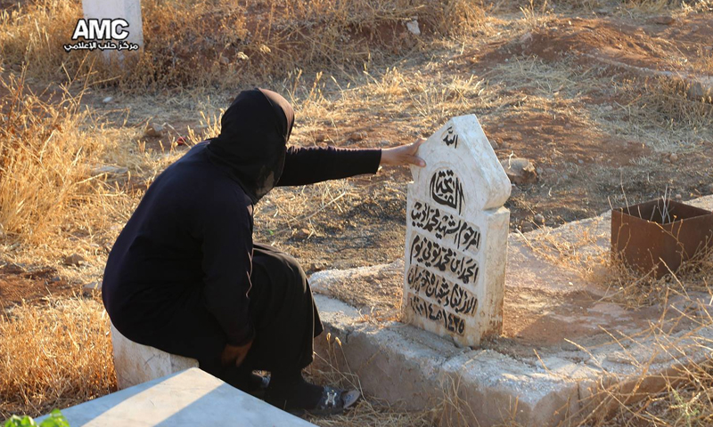 امرأة تجلس إلى جانب قبر شهيد في مقبرة مساكن هنانو - 6 تموز 2016 (مركز حلب الإعلامي)