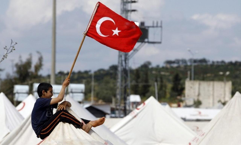 طفل سوري يرفع علم تركيا فوق المخيم (انترنت)