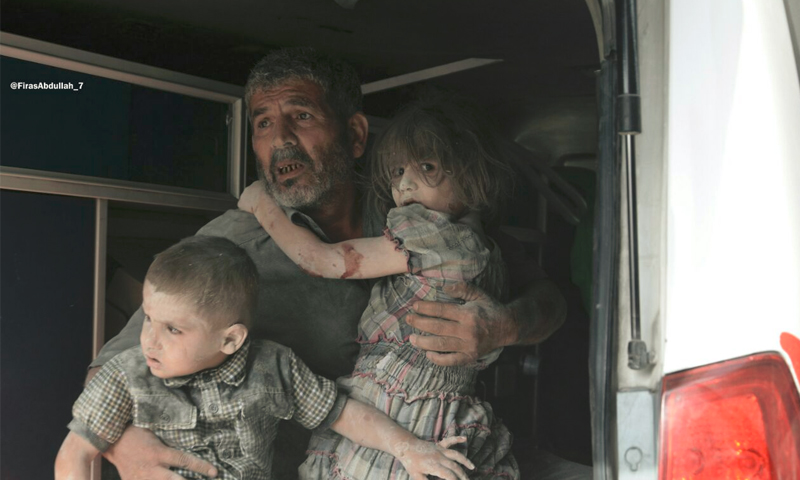 رجل يحتضن طفليه عقب الغارات على مدينة دوما - الثلاثاء 23 آب (ناشطون)