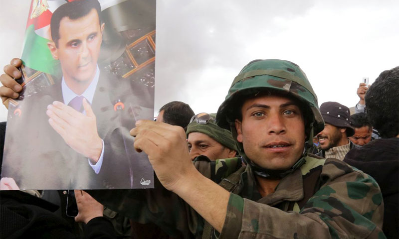 عنصر من قوات الأسد يحمل صورة بشار الأسد في ريف دمشق شباط 2016