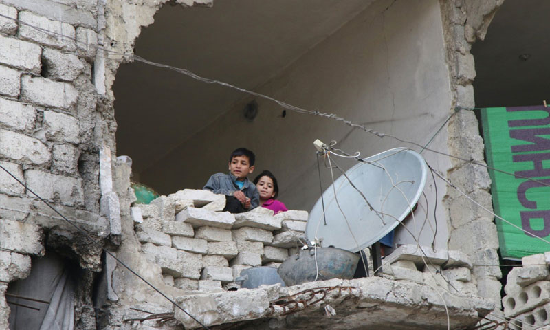 طفلان يطلان من منزلٍ مهدّم في حلب - شباط 2016 (AP)