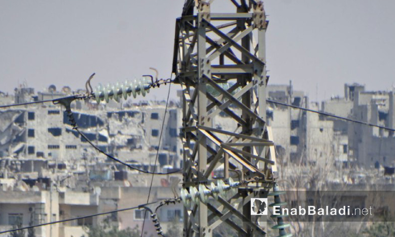 برج كهرباء في حي الوعر بحمص ويظهر في عمق الصورة الدمار في حمص القديمة (عنب بلدي)