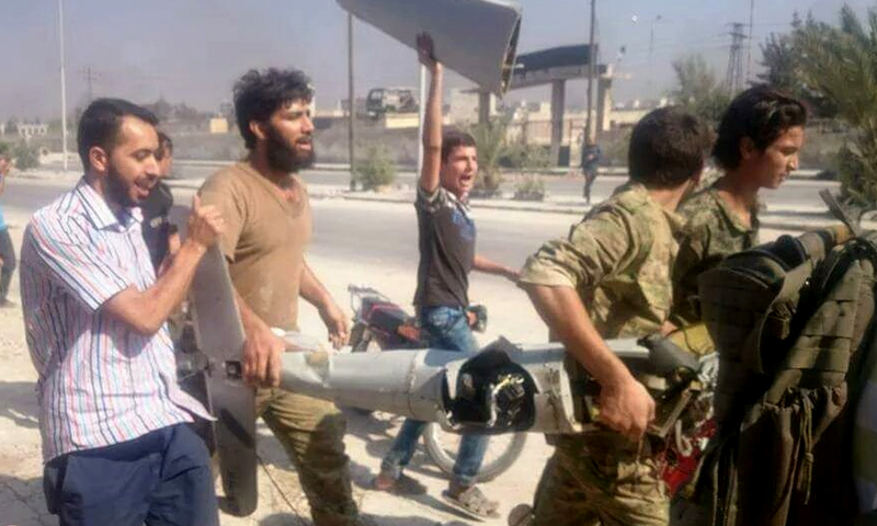 مدنيون وعسكريون يحملون حطام الطائرة في حي باب النيرب - الثلاثاء 2 آب (تويتر)