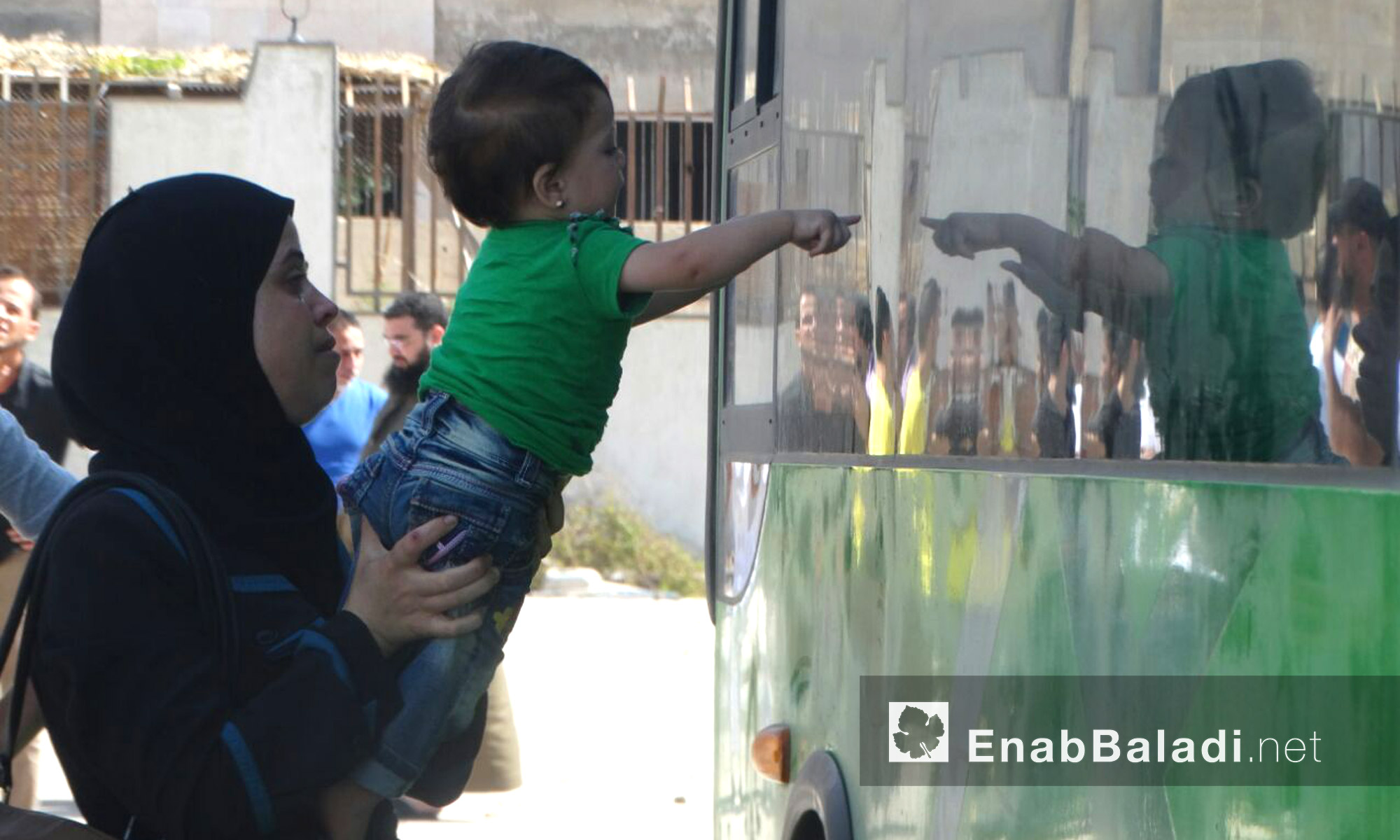 طفلة تشير بإصبعها إلى المقاتلين داخل الباص في حي الوعر - الخميس 23 أيلول (عنب بلدي)