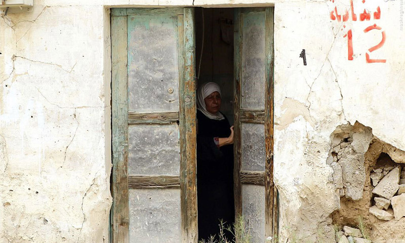 امرأة سورية تتفحص منزلها بعد العودة إليه في تدمر بريف حمص نيسان 2016 (AFP)