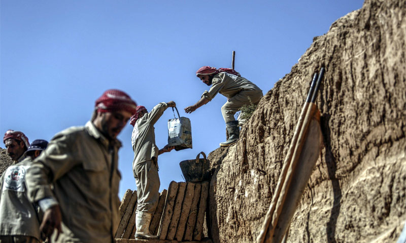 عمال يبنون قبور في مدينة دوما بريف دمشق (EPA)