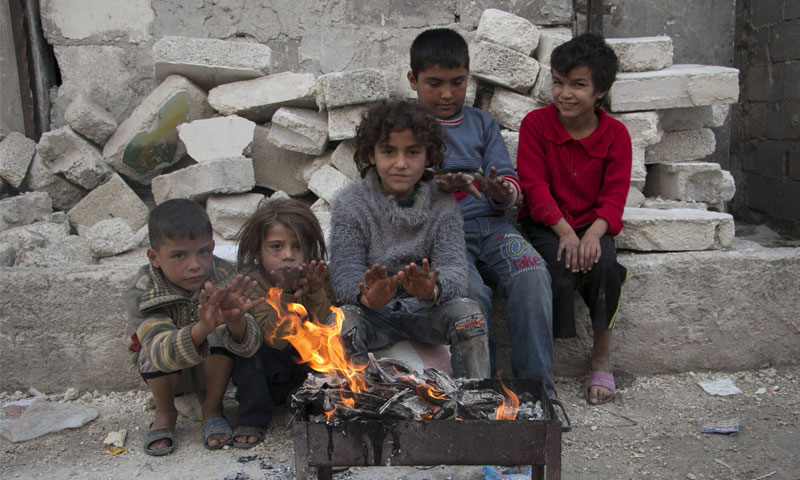أطفال سوريين ينالون قسطًا من الدفء في إحدى المخيمات (انترنت)