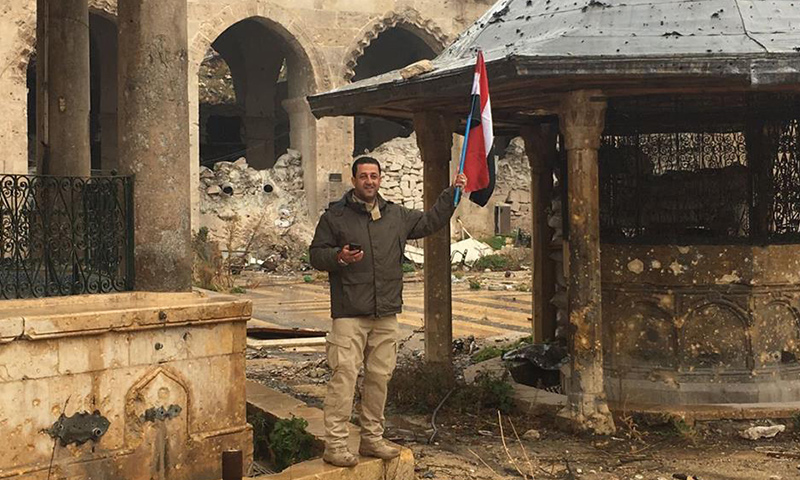 مدير مكتب قناة "العالم" الإيرانية في سوريا، حسين مرتضى، حاملًا علم النظام السوري، داخل الجامع الأموي الكبير في حلب- كانون الأول 2016 (فيس بوك)
