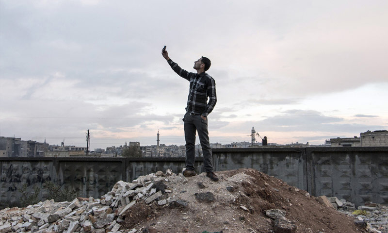مواطن يحاول التقاط شبكة أفضل لجواله شمال مدينة حلب - تشرين الثاني 2014 (كرم المصري - AFP)