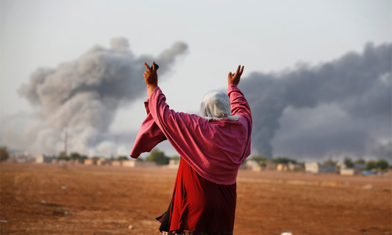 امرأة ترفع أصابع النصر إثر قصفٍ نفذّته مقاتلات أمريكية على مدينة كوباني على الحدود السورية- التركية
13 تشرين الأول 2014
(AP)