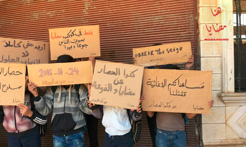 تعبيرية:أطفال بلدة مضايا في ريف دمشق يحملون مناشداتهم في لافتات - 24 تشرين الأول 2016 (صفحة هنا مضايا في فيس بوك)