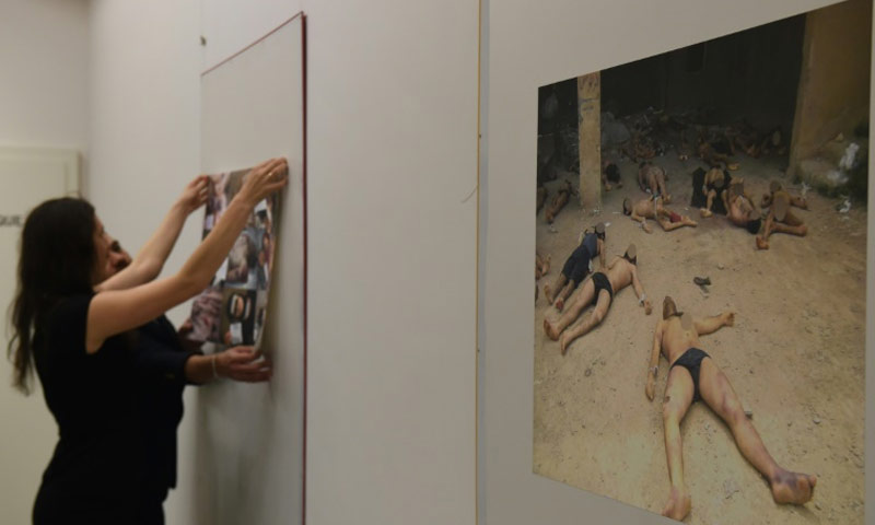 أعضاء في المنظمة السورية لضحايا الحرب يعلقون صورًا توثيقية لتعذيب السوريين داخل ومعتقلات النظام السوري، خلال معرض في جنيف في 17 اذار 2016 (AFP)
