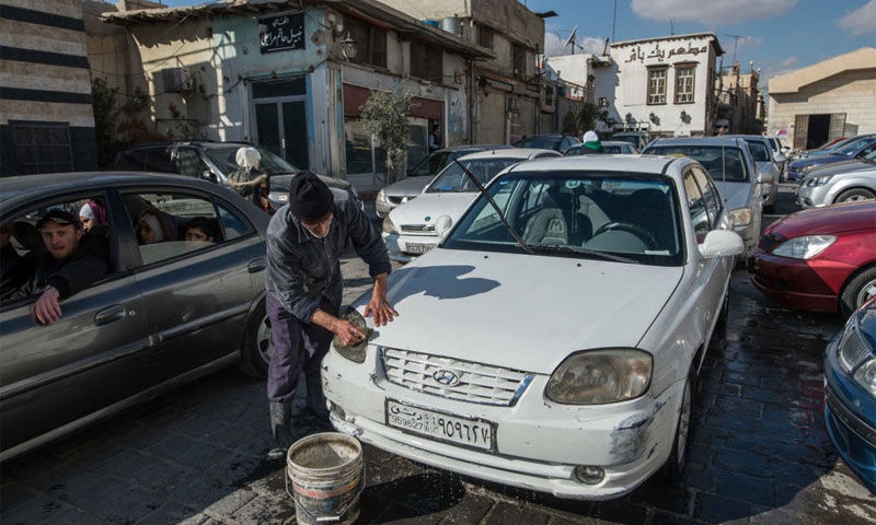 أحد سكان مدينة دمشق يقوم بتنظيف سيارته كانون الأول 2016(سبوتنيك)