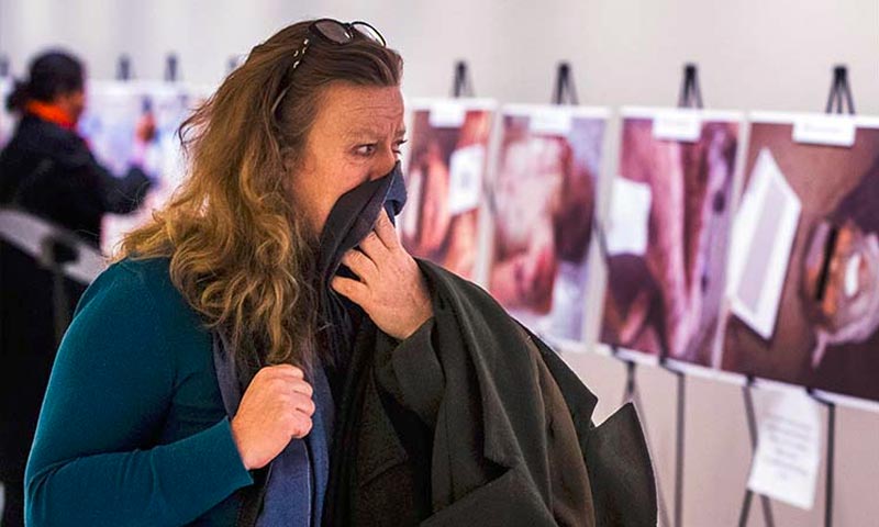 تعبيرية: امرأة تنظر بأسى إلى صور السوريين في معرض قيصر لضحايا التعذيب داخل مقر الأمم المتحدة- أيلول 2015 (إنترنت)
