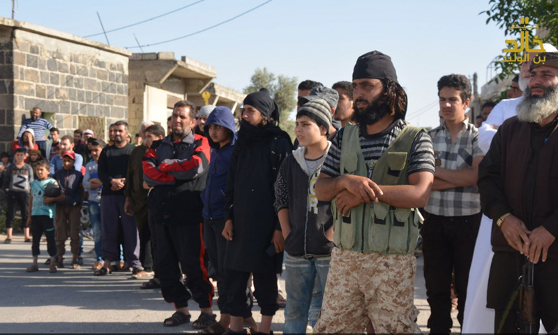 أهالي تسيل في ريف درعا الغربي يتجمهرون أمام مقاتلين لـ "جيش خالد" يقطعون رأس رجل بتهمة السحر- الأحد 30 نيسان 2017 (تلغرام)