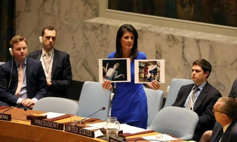 السفيرة الأمريكية لدى الأمم المتحدة، نيكي هيلي تحمل صور ضحايا مجزرة خان شيخون - نيسان 2017 (وكالات)