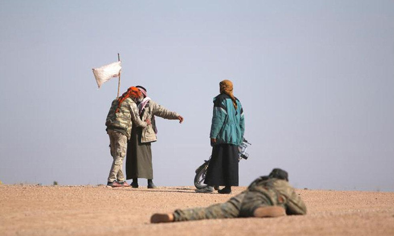 عنصر من قوات سوريا الديموقراطية يفتّش نازحين من مدينة الرقة- (رويترز)
