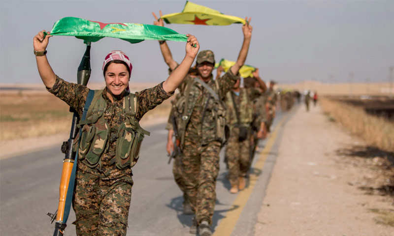 تعبيرية: مقاتلون ومقاتلات كرد يحملون علمهم شمال سوريا (رويترز)