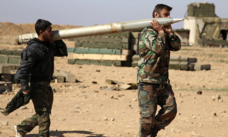 عناصران من قوات الأسد يحملان صاروخ غراد على الحبهات العسكرية في ريف الرقة الجنوبي - (انترنت)