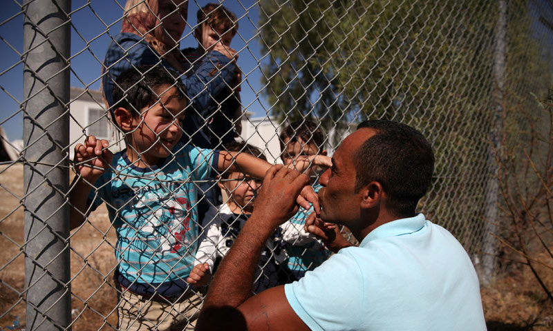 لاجئ سوري يعيش في قبرص يقبل أيدي اطفاله بعد وصولهم إلى مخيم للاجئين - 13 أيلول 2017 (رويترز)
