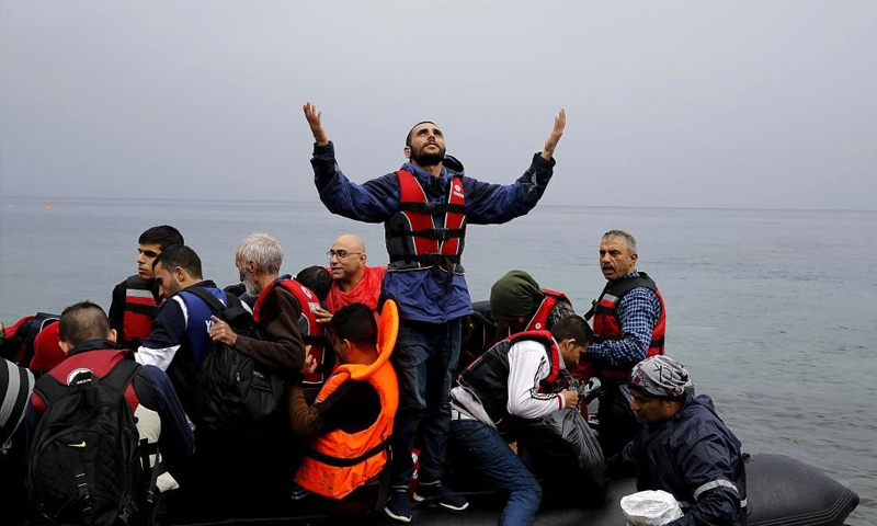 لاجئ سوري يشكر الله عند وصوله إلى جزيرة ليسبوس اليونانية مع مجموعة من اللاجئين - 23 كانون الأول 2016 (رويترز)