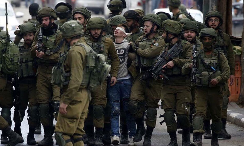 طفل فلسطيني بين مجموعة من الجنود الإسرائيلين في مدينة الخليل الفلسطينية (EFE)