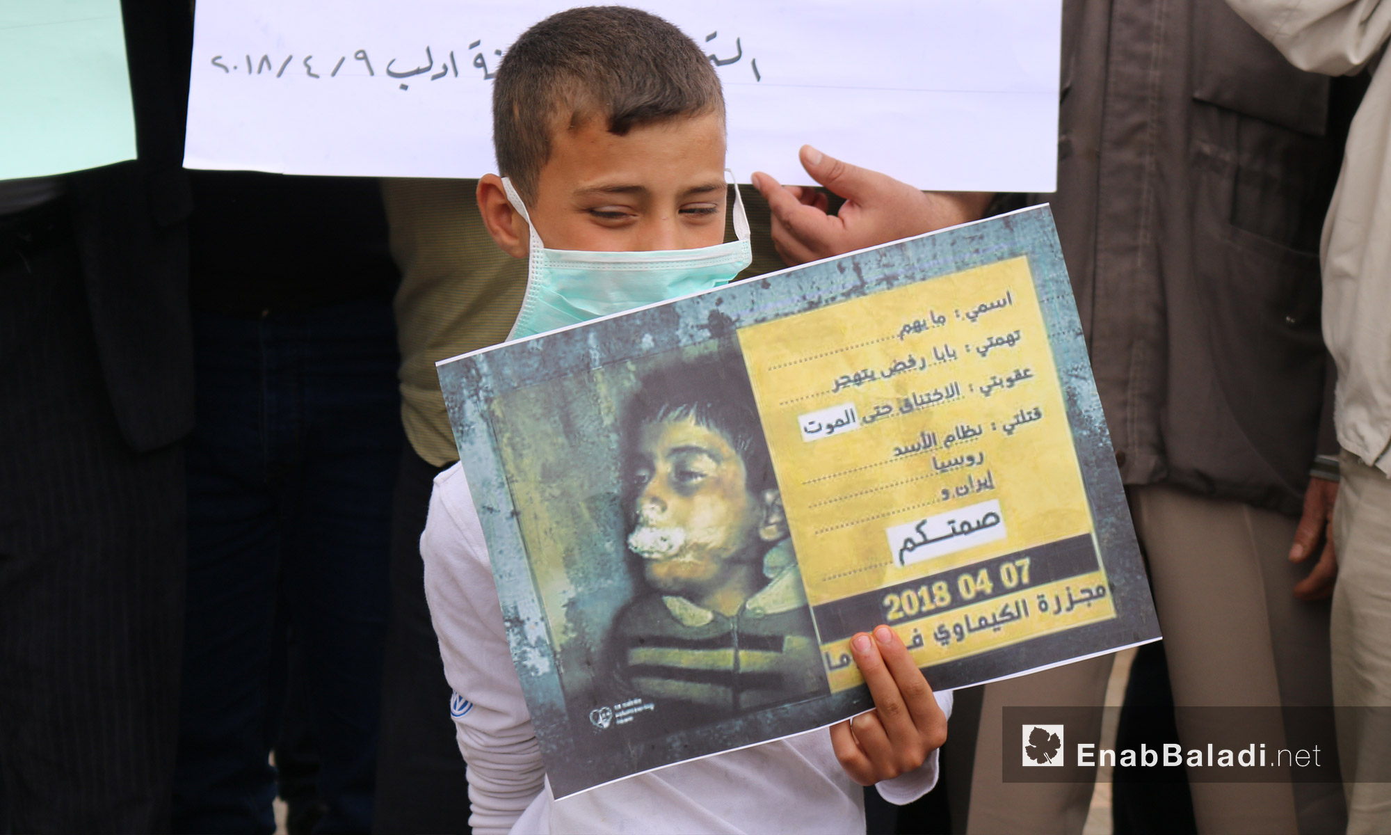 طفل يحمل صورة لأحد ضحايا الغازات السامة خلال وقفة تضامنية لأهالي إدلب مع دوما بعد مجزرة الكيماوي - 9 من نيسان 2018 (عنب بلدي)