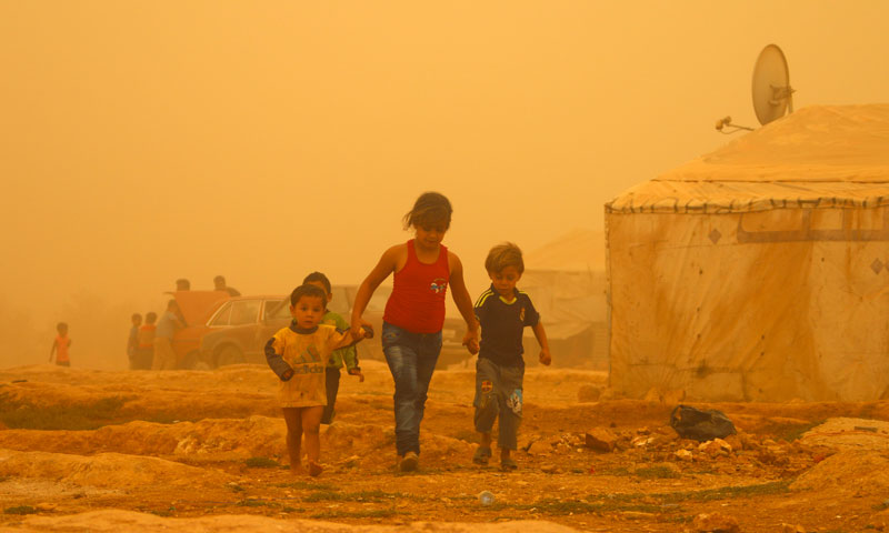 أطفال سوريون يمشون في مخيم بالبقاع اللبناني خلال عاصفة غبارية - 7 أيلول 2015 (AFP)