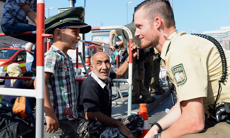 شرطي ألماني مع طفل سوري لاجئ (IB times UK)
