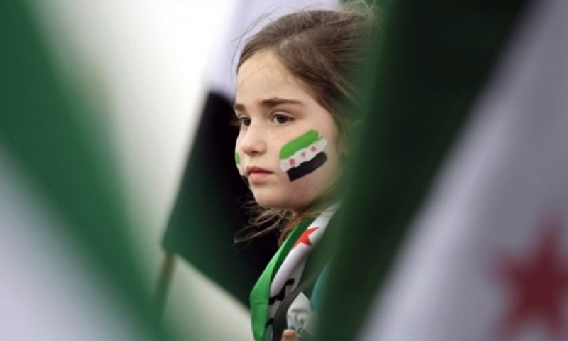 تعبيرة لفتاة ترسم علم الثورة السورية على وجهها