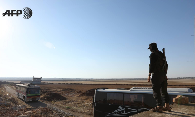مقاتل من فصائل المعارضة ينظر إلى حافلات تقل مقاتلي بلدتي كفريا والفوعة - 19 من تموز 2018 (AFP عمر حاج قدور)