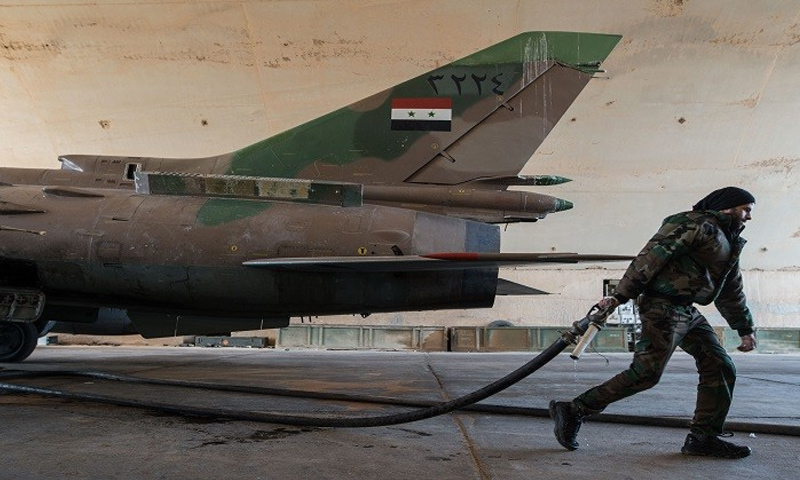 عنصر من قوات الأسد يعمل على تجهيز طائرة حربية نوع ميغ في مطار تي فور بريف حمص في سوريا - (انترنت)