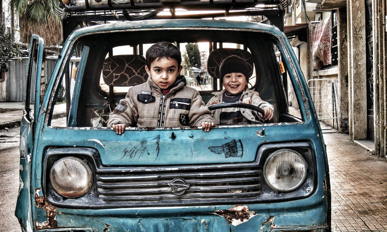 أطفال يلهون بسيارة معطلة في حي الوعر بحمص - 6 كانون الثاني 2015 (عدسة شاب حمصي)