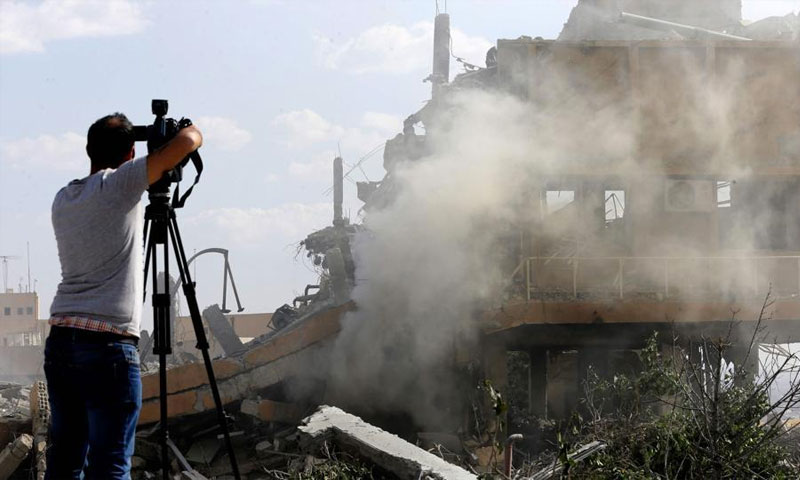 مصور سوري يلتقط صورًا لآثار قصف استهدف مركز البحوث العلمية شمال دمشق - نيسان 2018 (AFP)