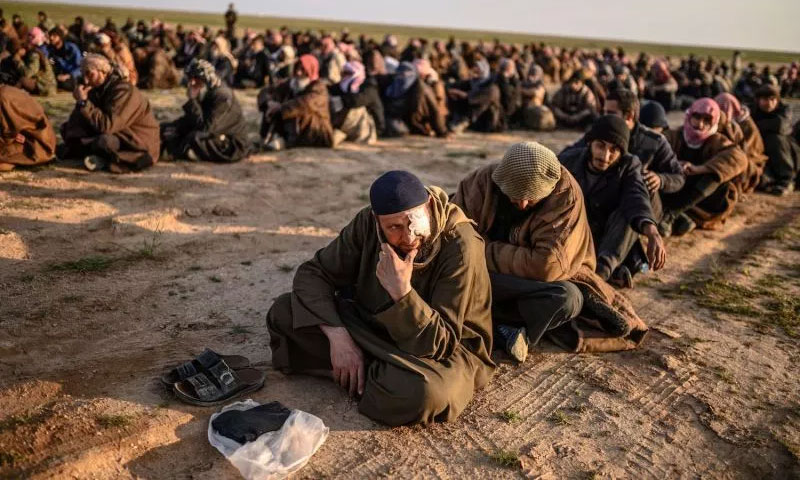 رجال يشتبه بانضمامهم لتنظيم الدولة الإسلامية بانتظار أن يتم تفتيشهم من قبل قوات سوريا الديمقراطية عقب مغادرتهم للباغوز - 22 من شباط 2019 (AFP)