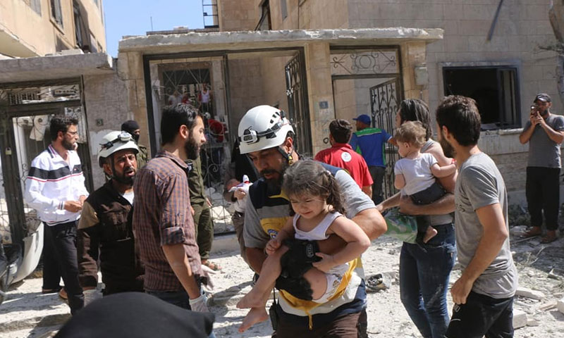 عناصر من الدفاع المدني يسعفون مدنيين تعرضوا لقصف جوي في حي القصور بمدينة إدلب 12 من تموز 2019 (الدفاع المدني السوري)