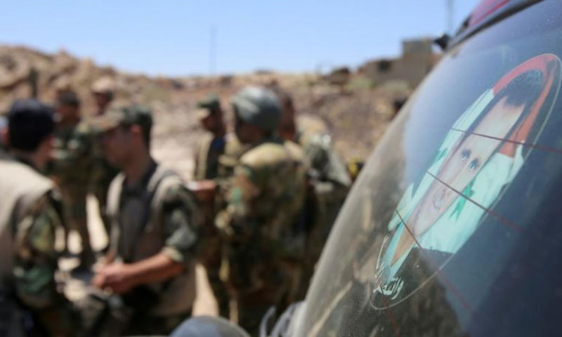 عناصر من قوات الاسد أمام صورة رئيس النظام السوري بشار الأسد على سياراة (AFP)