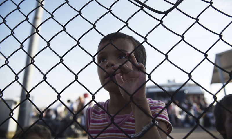 فتاة مهاجرة تنظر عبر سياج شمال اليونان - 2 أيلول 2019 (AP)