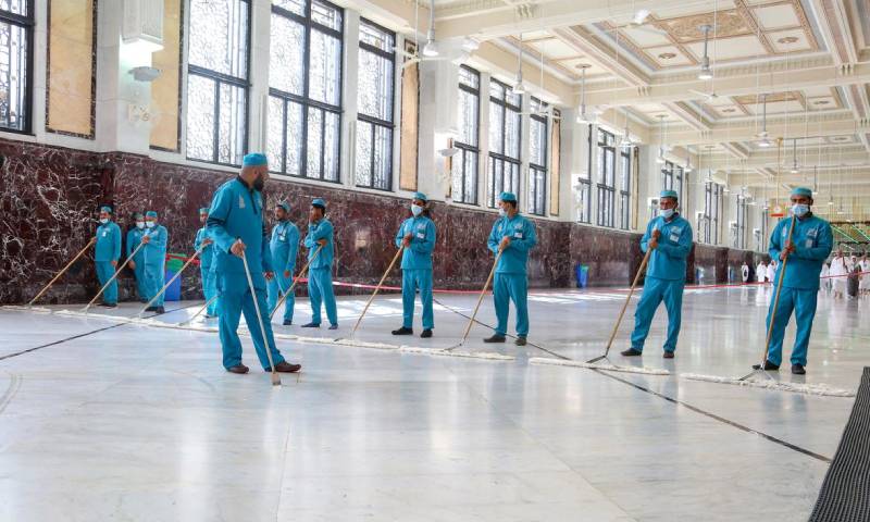 عمال نظافة يضعون كمامات للوقاية من فيروس "كورونا المستجد" بالمسجد الحرام بمدينة مكة المكرمة 3 من آذار 2020 - (رويترز)