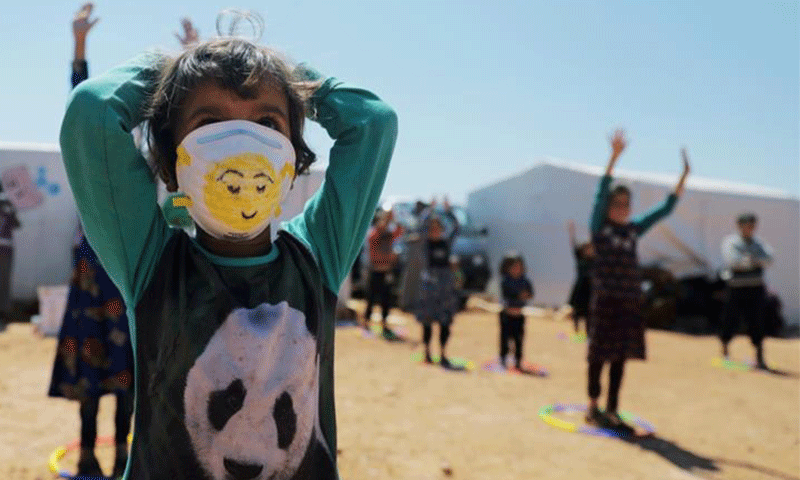 طفلة سورية ترتدي الكمامة للوقاية من فيروس "كورونا المستجد" في إحدى مخيمات النازحين في شمال غربي سوريا - (Khalil Ashawi / Reuters)