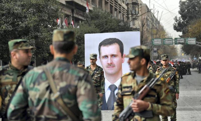 جنود سوريون يمرون أمام صورة رئيس النظام السوري بشار الأسد خلال ذكرى مرور عام على دخول قوات النظام مدينة حلب- 21 من كانون الأول 2017 (AFP)