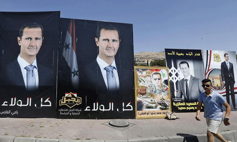 رجل سوري يمر بجوار ملصقات لرئيس النظام السوري، بشار الأسد، المرشح للانتخابات الرئاسية في العاصمة لعام 2021 في العاصمة دمشق- 18 من أيار 2021 (AFP)